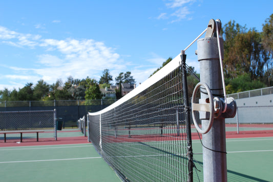 Filet de tennis correctement ajusté sur un court conformément aux normes de hauteur en France.